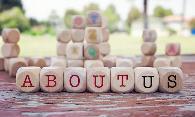The words About Us spelled out in wooden blocks, introducing the practice
